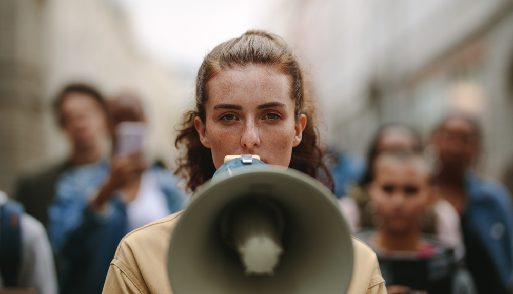 A woman holding a megaphone in front of a crowd at a political rally